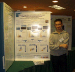 Poster prize winner Nicholas Marron smiling and standing next to the winning poster hung up.