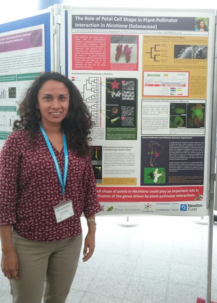 Poster prize runner-up Gabriela Doria smiling and standing in front of a stand displaying the runner-up poster.