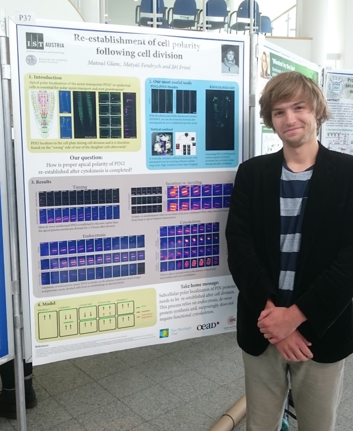 Poster prize winner Matous Glanc smiling and standing in front of a stand displaying the winning poster.