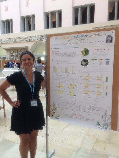 Poster prize runner-up Katherine Barragan-Fonseca smiling and standing in front of the runner-up poster hung on a board.