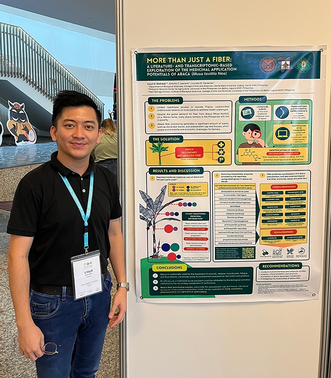 Poster prize runner-up Lloyd Balinado smiling and standing in front of the runner-up poster mounted on the wall.