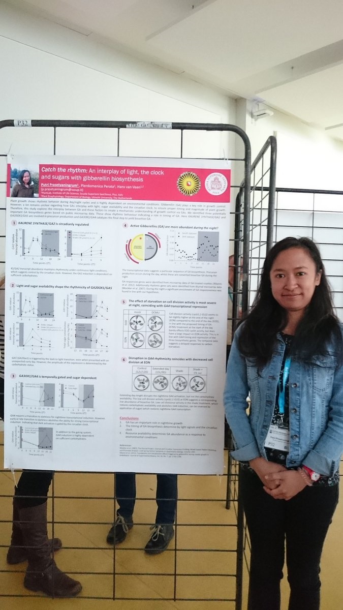 Poster prize winner Putri Prasetyaningrum smiling and standing next to the winning poster hung up.