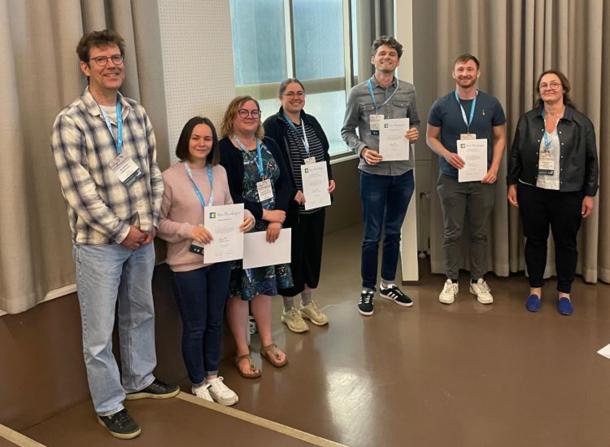 Five prize winners stand with their certificates between Bjorn Lindahl and Maarja Opik.