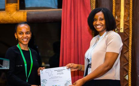 Bernice Wareru accepts her certificate for first prize for best oral presentation from Patience Chatukuta, at the African Plant Genomics Symposium