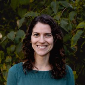 Camille Delavaux in front of green leaves, wearing a teal sweater