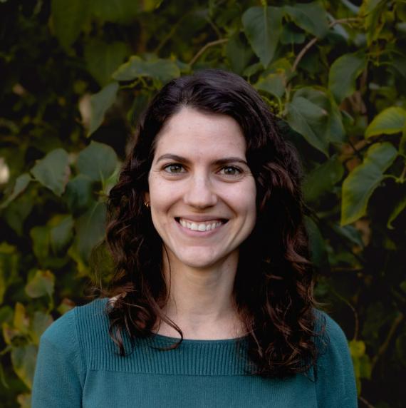 Camille Delavaux in front of green leaves, wearing a teal sweater