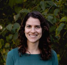 Camille Delavaux in front of green leaves, wearing a teal sweater