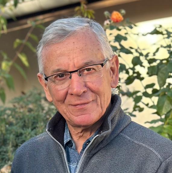 Francis Martin wearing a grey fleece and glasses stood in front of plants