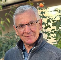 Francis Martin wearing a grey fleece and glasses stood in front of plants