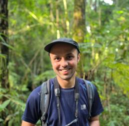 Gianluca	Cerullo holding a pair of binoculars in the forest