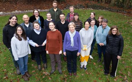 A group of colleagues standing in a grassy woodland clearing.