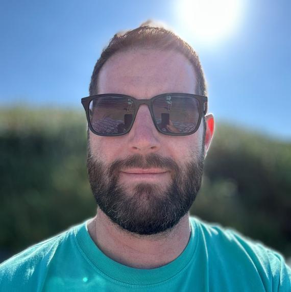 James McDonald in a green t-shirt and sunglasses, outdoors