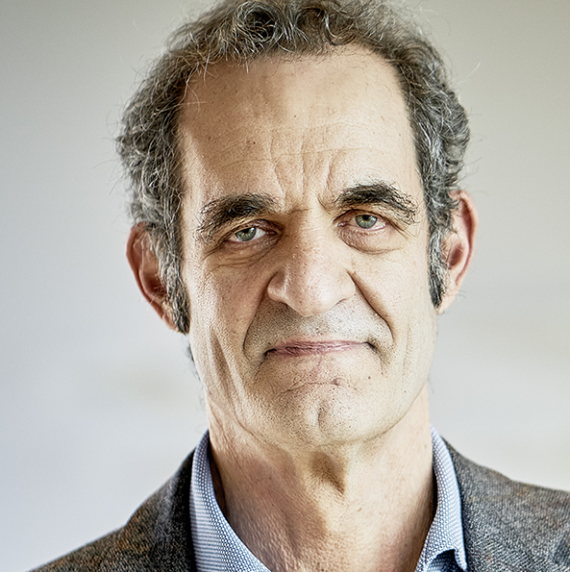 Headshot of Jonathan Gershenzon in a grey suit in front of a light taupe background