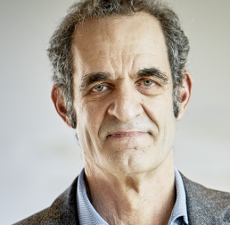 Headshot of Jonathan Gershenzon in a grey suit in front of a light taupe background