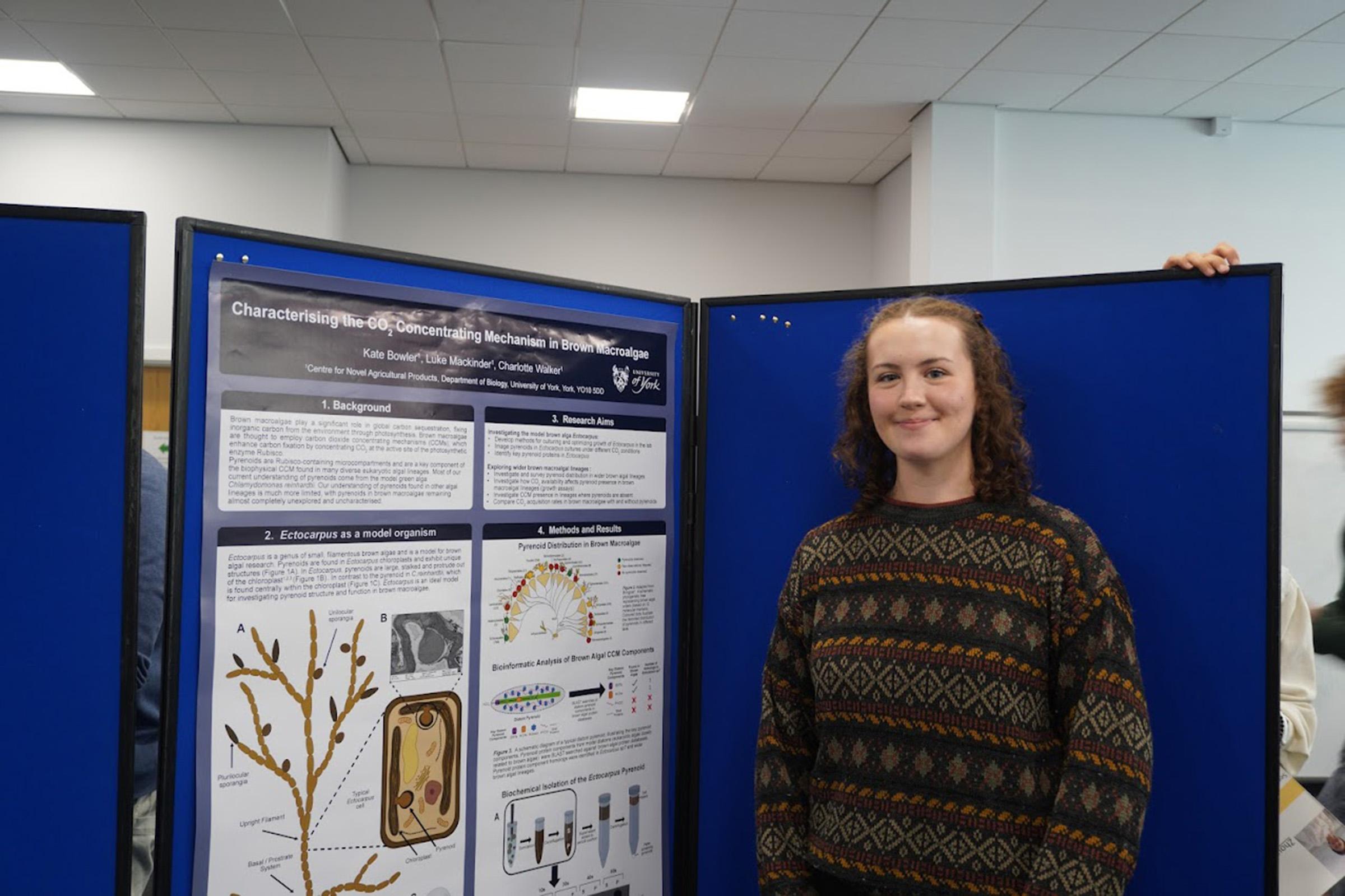 Kate Bowler standing next to her poster