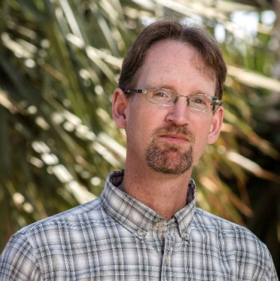 Photo of Kevin Hultine.  a man with brown hair, glasses and a beard, with a check shirt.