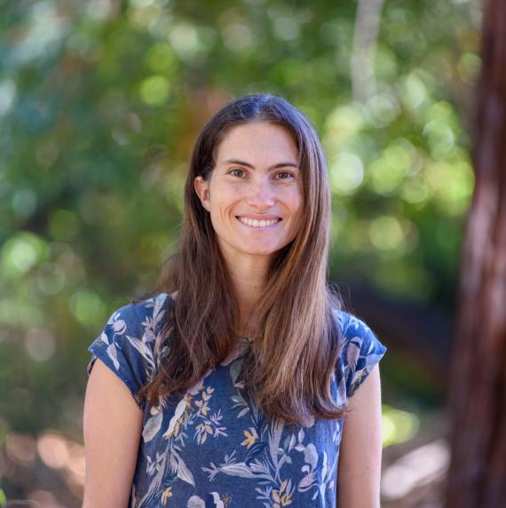 Miranda Redmond, wearing a blue top, with an out of focus forest behind her