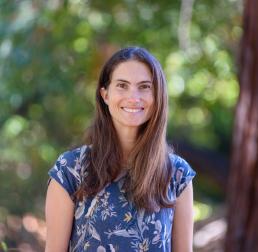 Miranda Redmond, wearing a blue top, with an out of focus forest behind her