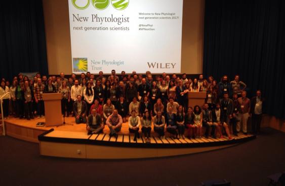 Group picture of the over 100 attendees of the Next Generation Scientists event at the John Innes Centre in Norwich in 2017. This is inside a large lecture hall with the attendees standing in five rows on the stage.