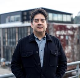 Rodrigo A. Gutiérrez wearing a black jacket stood in front of a building