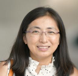 Xiaodong  Xu wearing a black and white top in front of a grey background