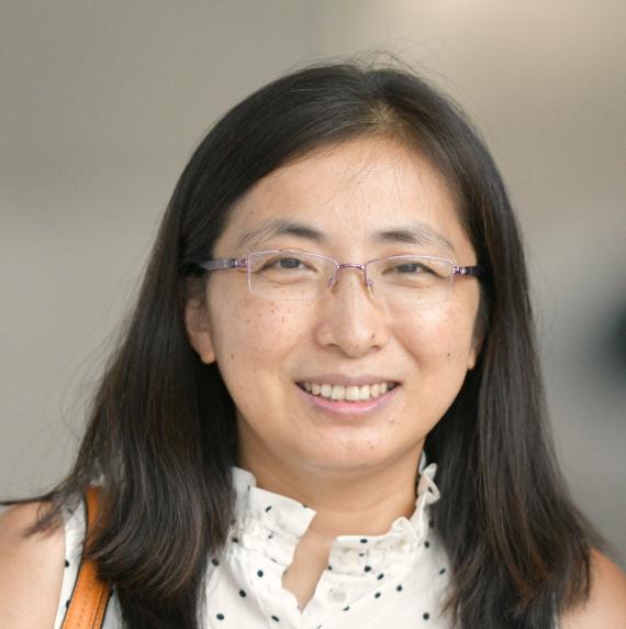Xiaodong  Xu wearing a black and white top in front of a grey background