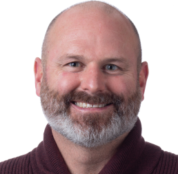 Todd Michael wearing a maroon jumper in front of a white background