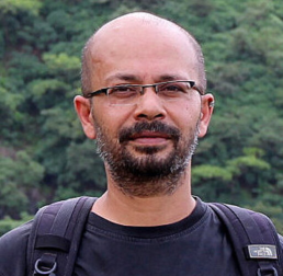 Deepak Barua in a black t-shirt wearing a backpack, outside