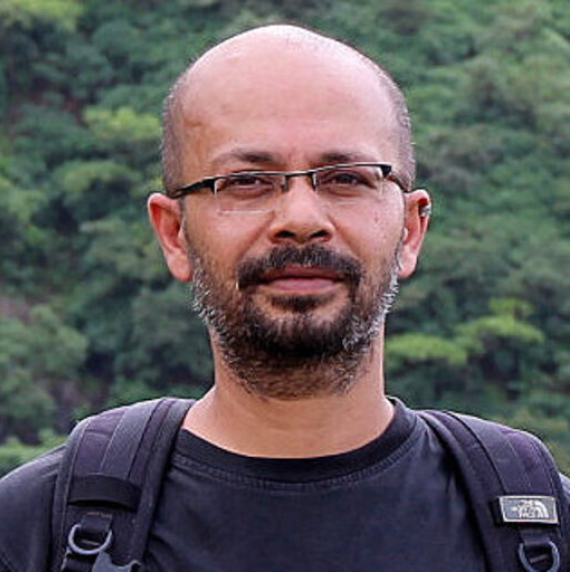 Deepak Barua in a black t-shirt wearing a backpack, outside