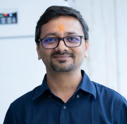 Ashutosh Srivastava in a navy blue shirt in front of a white background