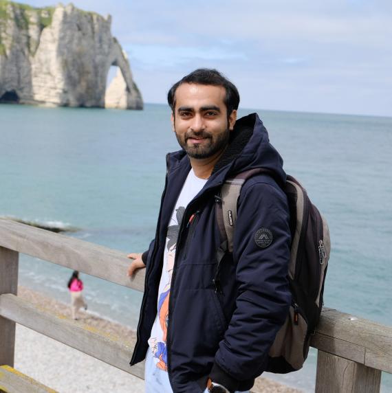 Ravi Suresh Devani stood on a walkway above a beach, with cliffs in the background