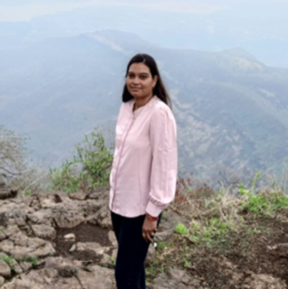 Arati Vasav wearing a pink shirt, stood outdoors with mountains in the background