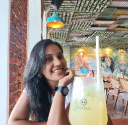 Sonal Talekar sat in a restaurant, smiling, with a yellow drink in front of her