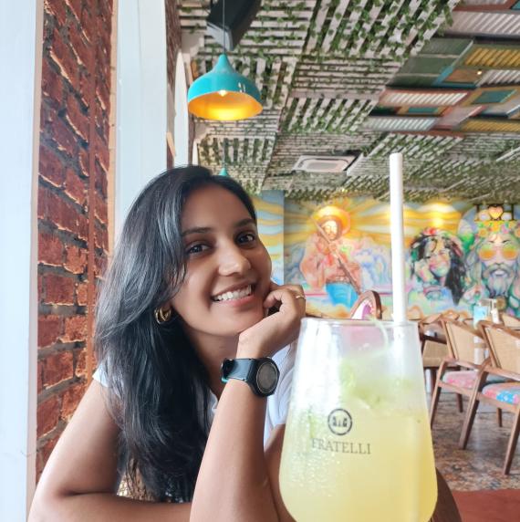 Sonal Talekar sat in a restaurant, smiling, with a yellow drink in front of her