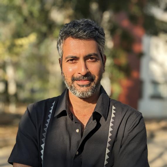 Ashish	Nerlekar wearing a black shirt, arms crossed and stood outside
