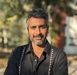 Ashish	Nerlekar wearing a black shirt, arms crossed and stood outside