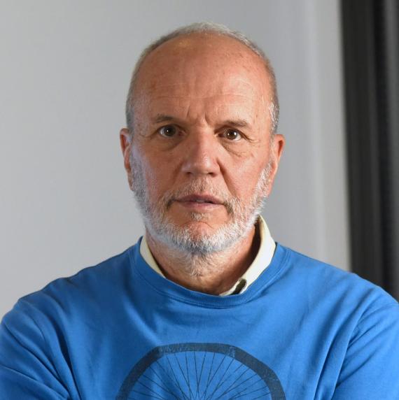 Ricardo Villalba wearing a blue jumper in front of a grey background