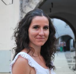 Rocío Hernández-Clemente, in a white top, standing in front of an arch