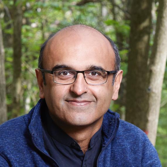 Yadvinder Malhi in a blue jumper in front of a forest background